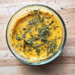 glass bowl with soup in it and parsley on top