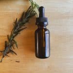 rosemary laying next to a brown tinted dropper bottle