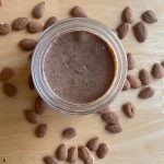 almond butter on a counter with whole almonds scattered around