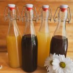 four bottles of water kefir with daisies to the right of them