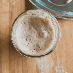 sourdough starter in a glass jar on a wooden surface