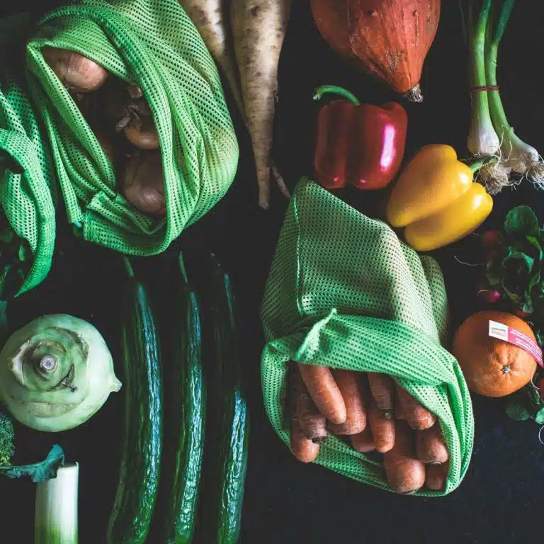 vegetables on a table coming out of reusable produce bags