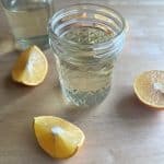 homemade simple syrup with oranges on a wood surface