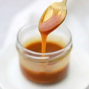caramel sauce dripping off a spoon into a jar